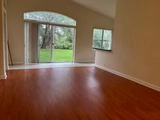 a view of an empty room with wooden floor and a window