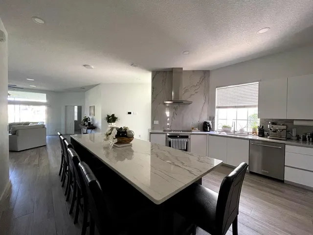 a kitchen with a dining table chairs and wooden floor