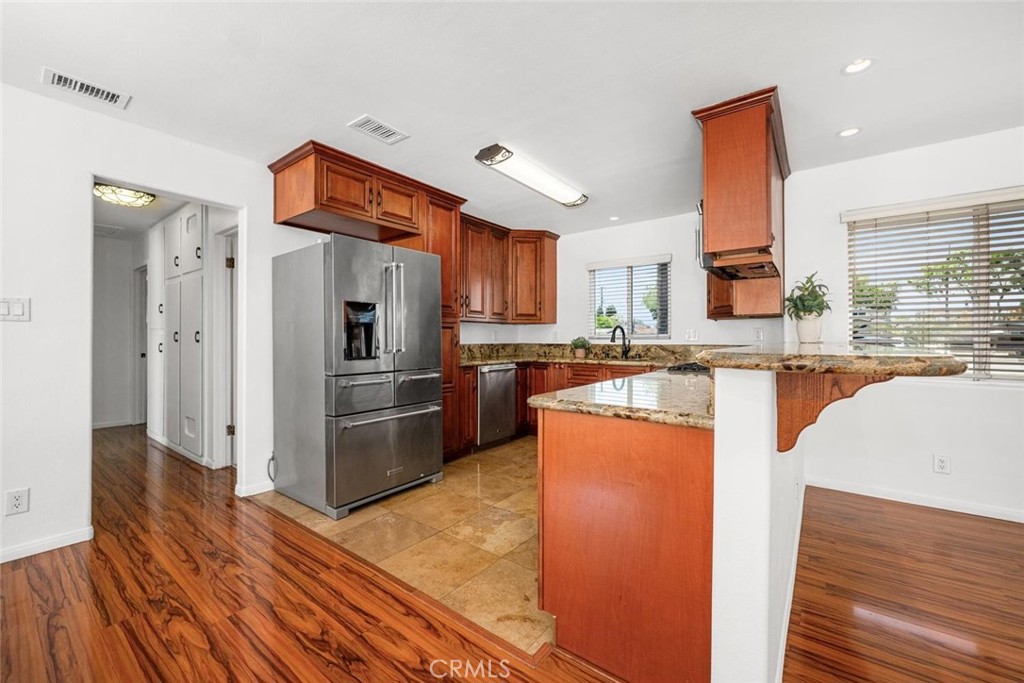 1238 North Studebaker Road Long Beach, CA 90815 - Photo 12 of 47 a kitchen with stainless steel appliances granite countertop a refrigerator a stove and a sink with wooden floors