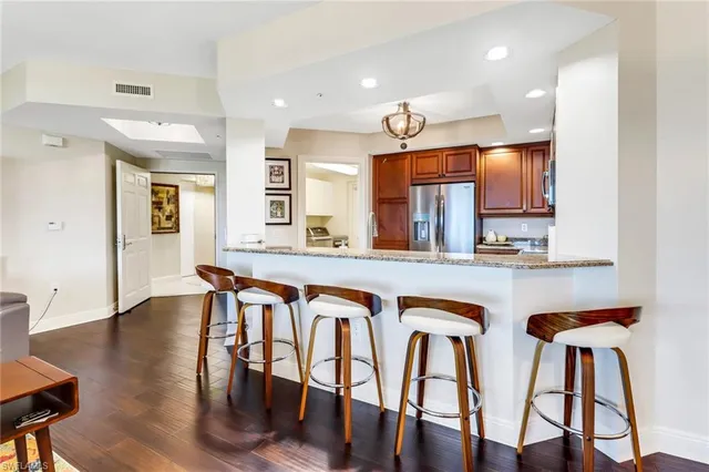 a very nice looking kitchen with granite countertop a table chairs stove a sink and a refrigerator
