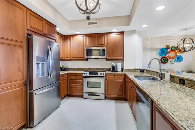 a kitchen with stainless steel appliances granite countertop a refrigerator a stove and a sink with cabinets