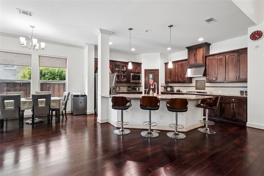 6715 Castillo Street Irving, TX 75039 - Photo 4 of 24 a kitchen with stainless steel appliances kitchen island granite countertop a dining table and chairs with wooden floor