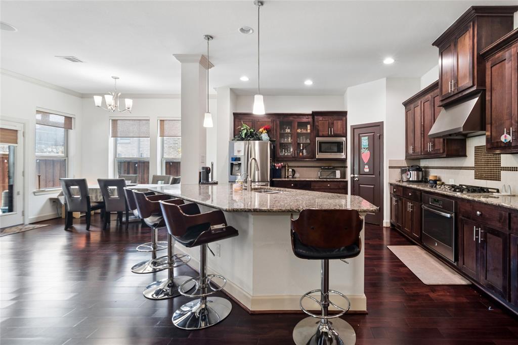 6715 Castillo Street Irving, TX 75039 - Photo 5 of 24 a kitchen with stainless steel appliances granite countertop a stove top oven a refrigerator a stove and a dining table with wooden floor