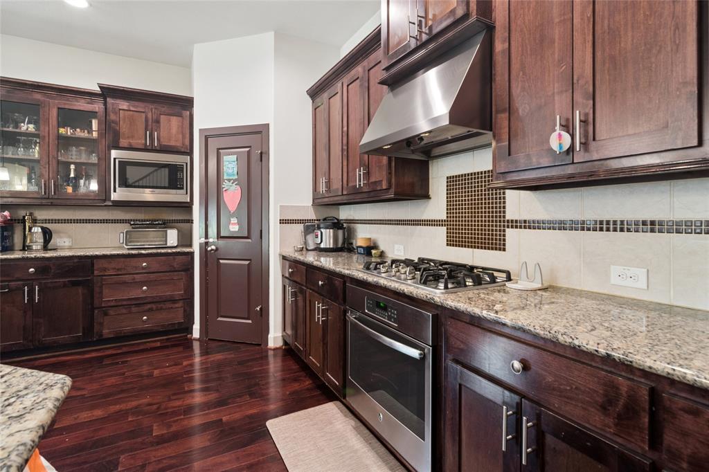 6715 Castillo Street Irving, TX 75039 - Photo 6 of 24 a kitchen with stainless steel appliances granite countertop a stove and a wooden cabinets