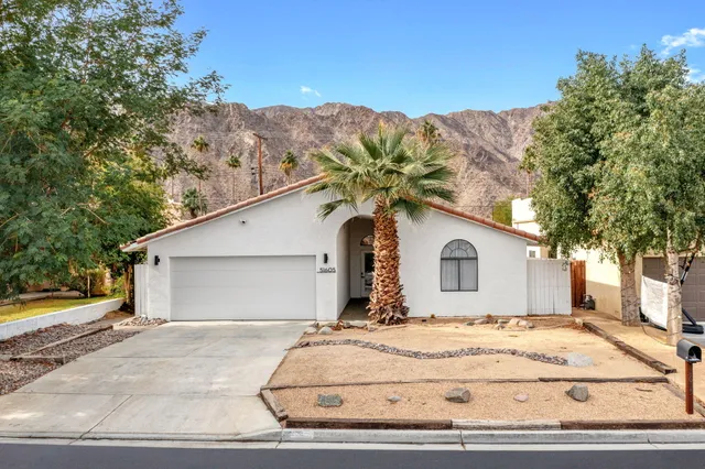 a view of a white house with a yard and large trees