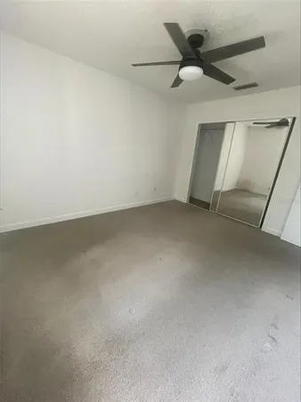 an empty room with ceiling fan and window