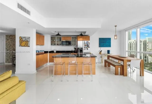 a kitchen with stainless steel appliances kitchen island granite countertop a stove a sink a dining table and chairs