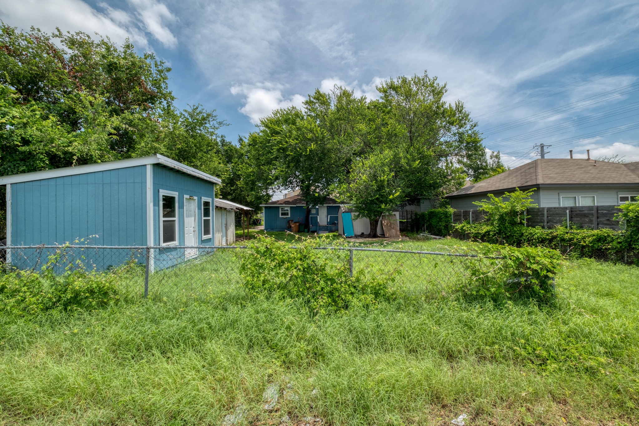 6409 Del Monte Road Austin, TX 78741 - Photo 8 of 15 A versatile backyard features a vibrant blue shed, offering ample storage and utility.