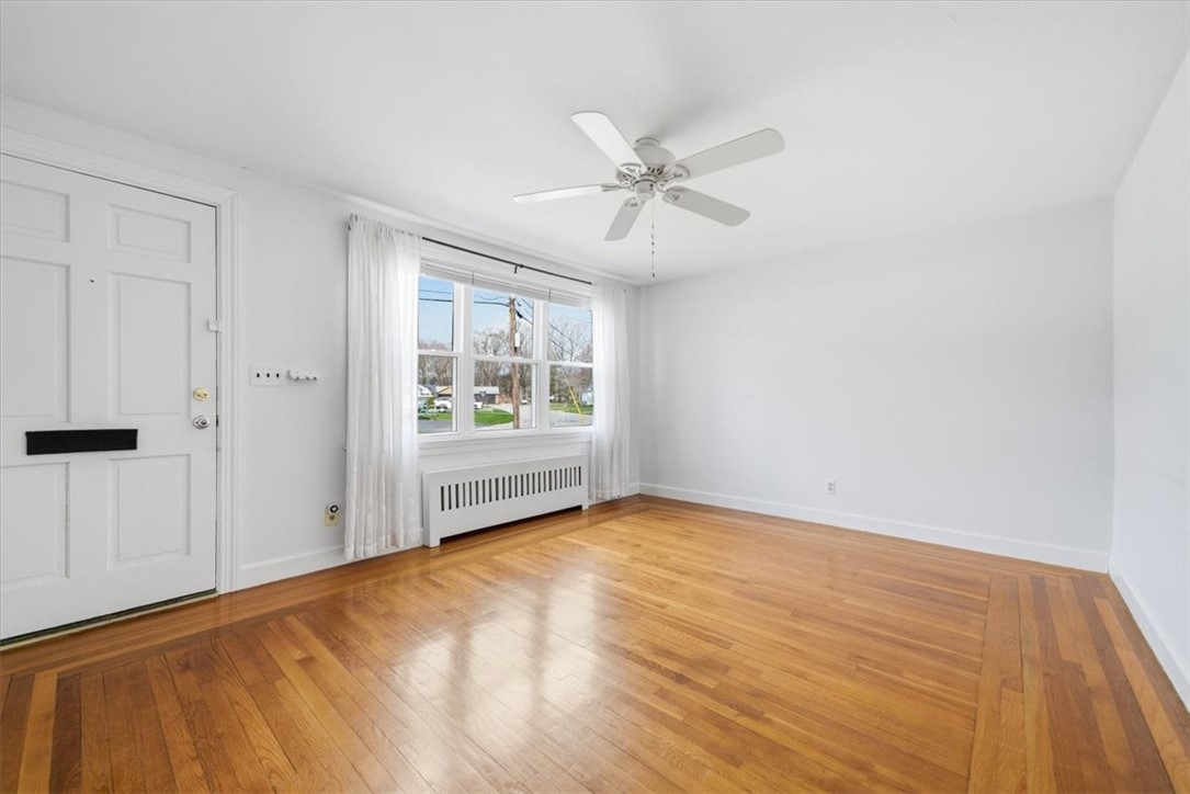 28 Glenbrook Road Warwick, RI 02889 - Photo 8 of 43 Sunlight pours through oversized windows, illuminating gleaming hardwood floors and a spacious living room that feels both comfortable and refined.