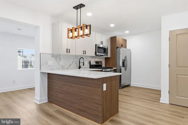 a kitchen with stainless steel appliances granite countertop a sink a stove a refrigerator and island with wooden floor