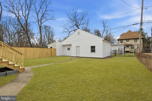 a view of a white house with a large tree with wooden fence