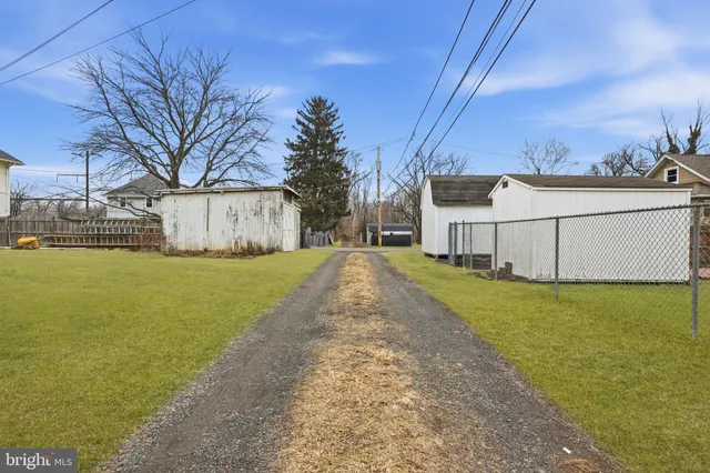 a view of a white house with a big yard and large tree