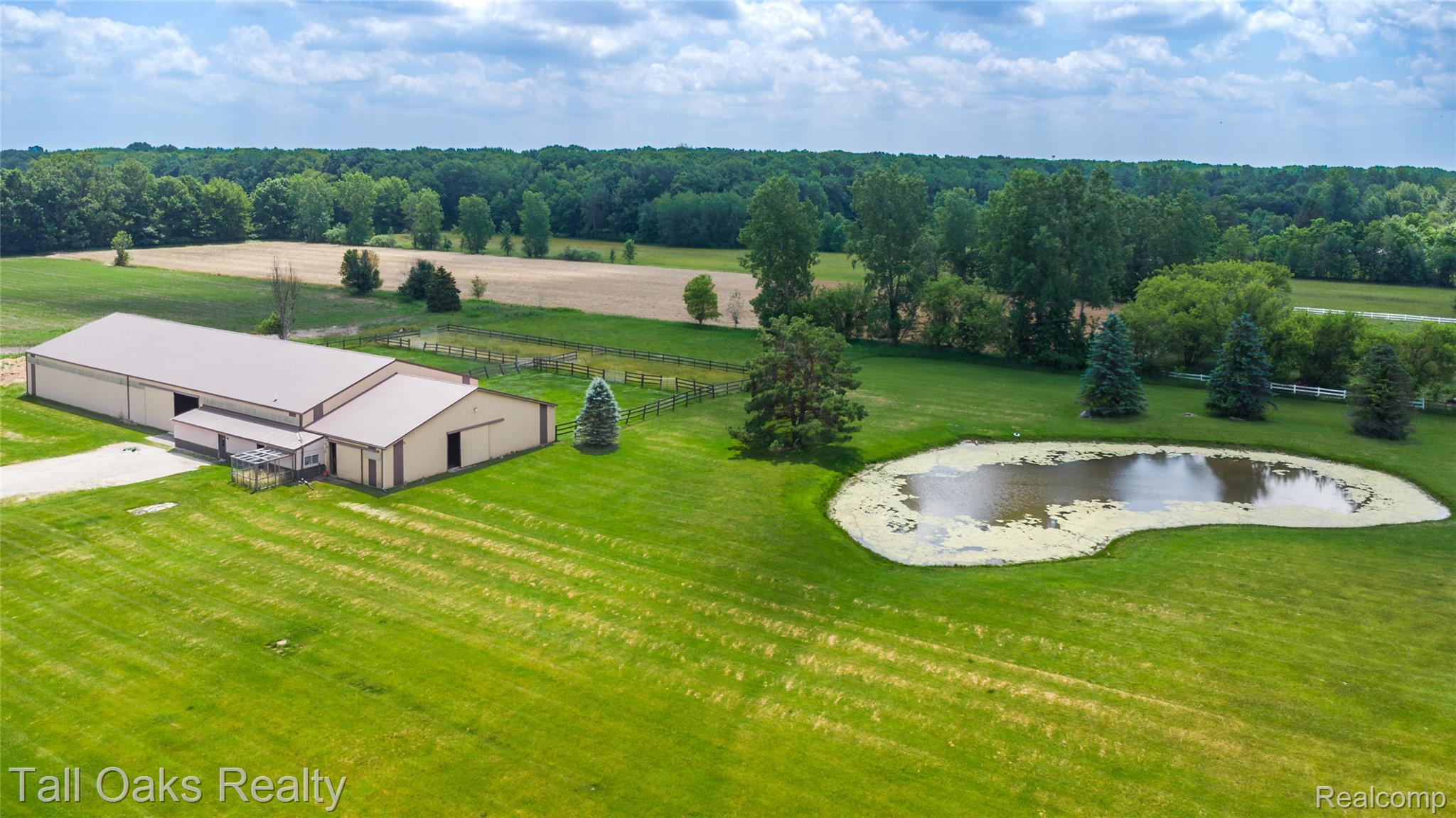 79330 Capac Road Armada, MI 48005 - Photo 3 of 42 Expansive property featuring a large outbuilding with a metal roof, a private pond, and vast green areas