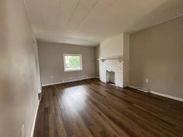 an empty room with wooden floor and window
