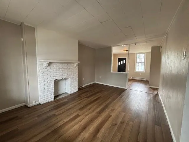 an empty room with wooden floor and fireplace