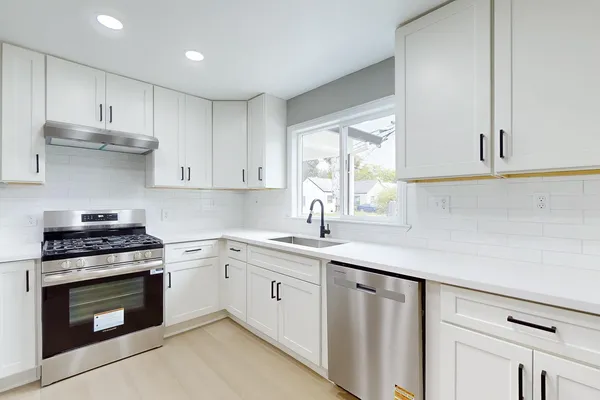 a kitchen with white cabinets stainless steel appliances and sink
