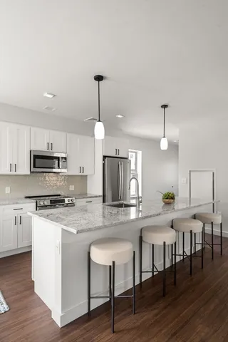 a kitchen with stainless steel appliances granite countertop a stove top oven a refrigerator a sink and a dining table with wooden floor