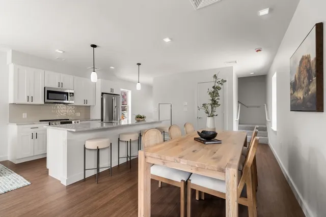 a kitchen with stainless steel appliances granite countertop a kitchen island hardwood floor sink stove dining table and chairs