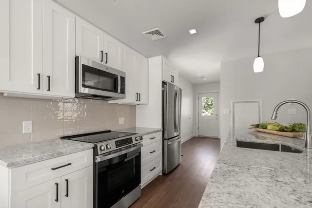 a kitchen with stainless steel appliances granite countertop a stove a sink and a microwave