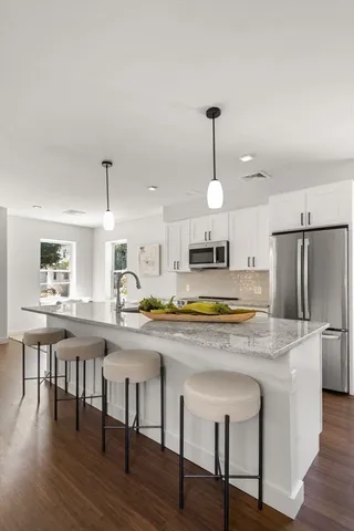 a kitchen with stainless steel appliances granite countertop a stove a sink a refrigerator a dining table and chairs