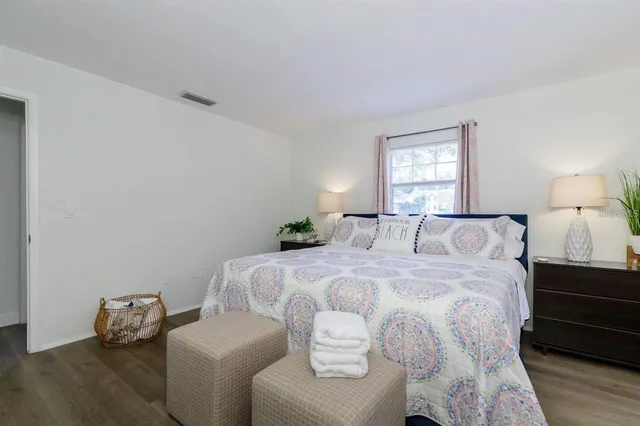 a large bed sitting in a bedroom next to a window with wooden floor