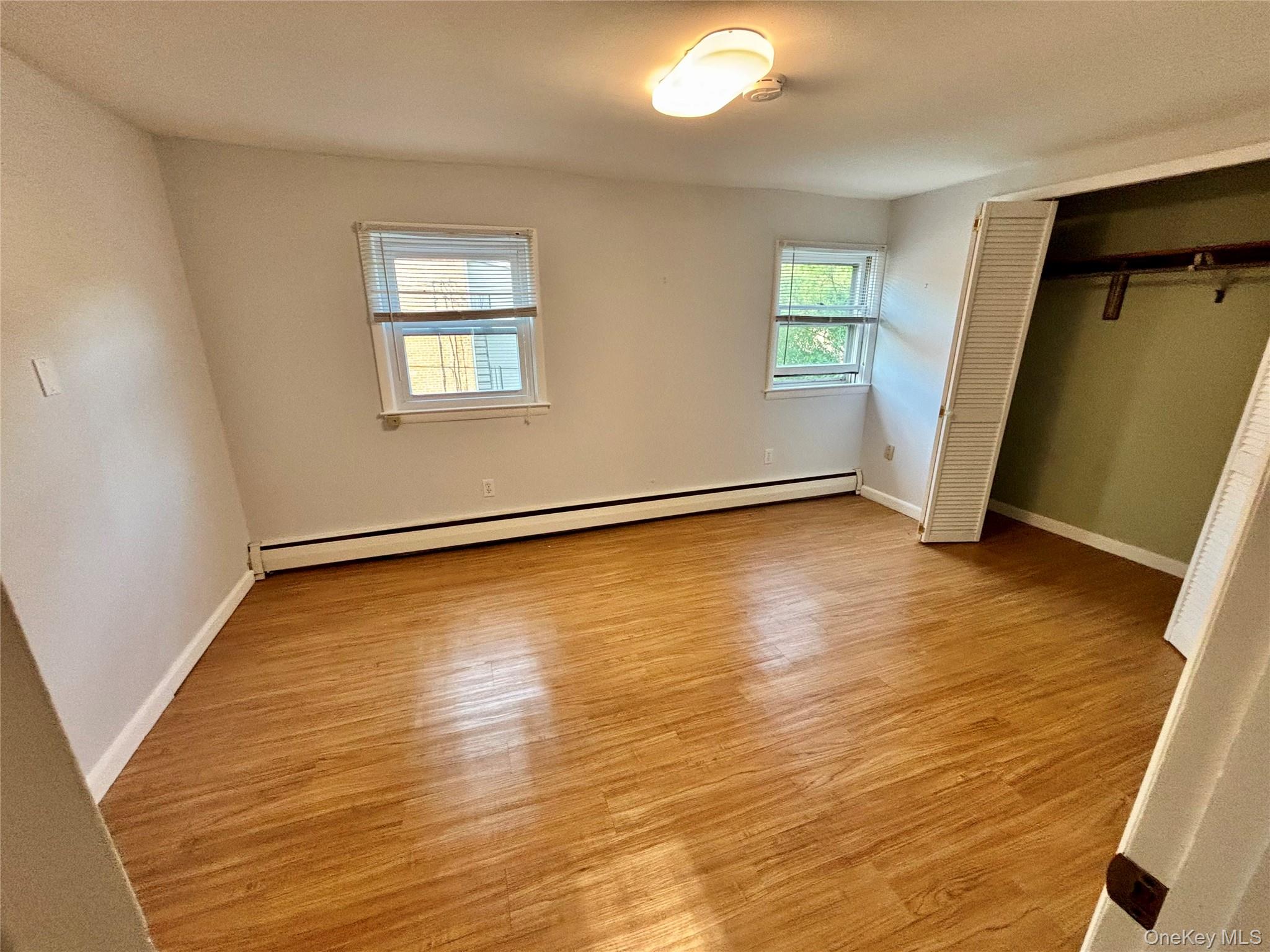 49 North Chestnut Street Beacon, NY 12508 - Photo 19 of 41 Unfurnished bedroom with baseboard heating, wood finished floors, a closet, and baseboards