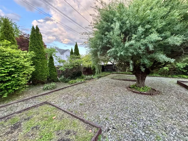 a view of a white house next to a road and yard