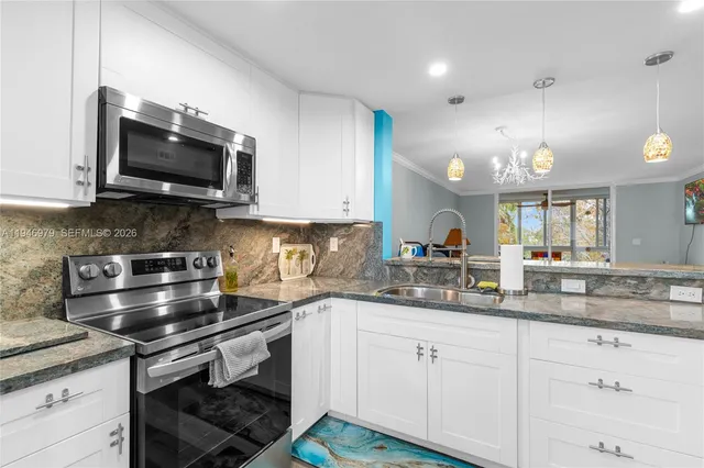 a large kitchen with granite countertop a sink and cabinets