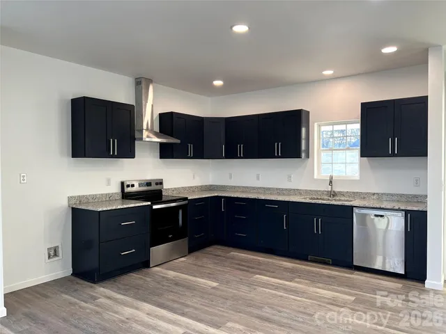 a kitchen with stainless steel appliances granite countertop wooden cabinets a sink a stove a refrigerator and black granite counter tops