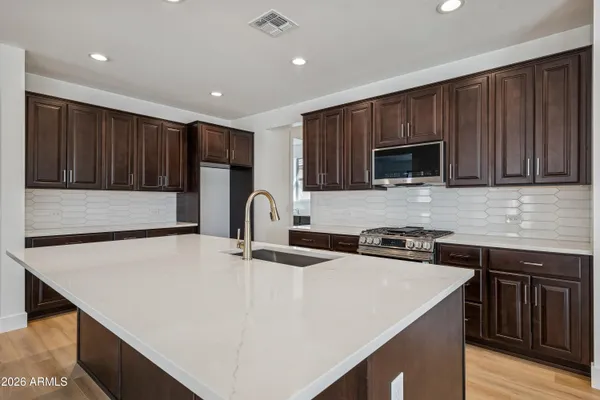a kitchen with stainless steel appliances a stove a sink a microwave a refrigerator and cabinets