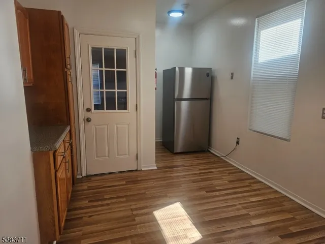an empty room with wooden floor and a hallway