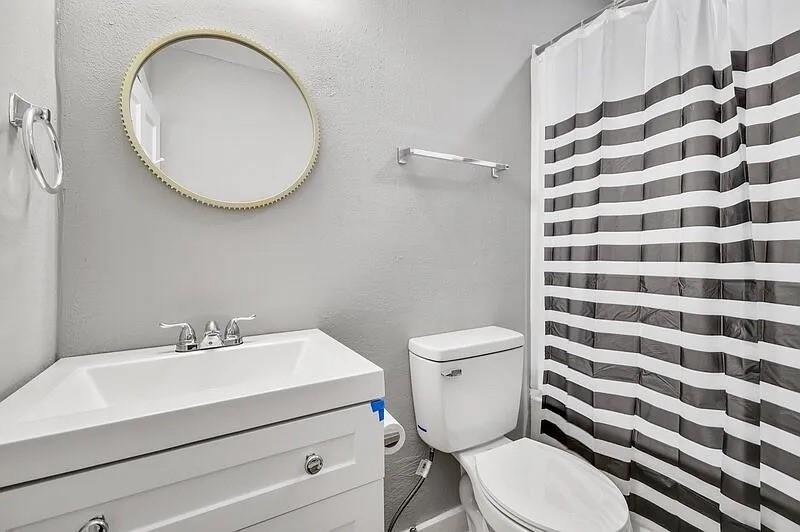 216 East Division Street Pilot Point, TX 76258 - Photo 16 of 17 Bathroom featuring a white vanity with integrated sink, chrome faucet, and round mirror