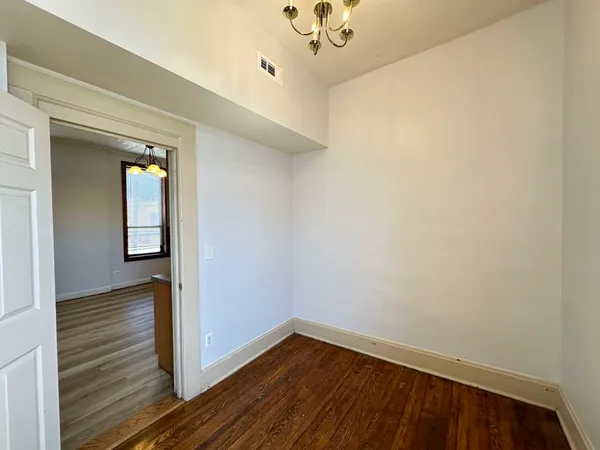 a view of a hallway with wooden floor and a chandelier