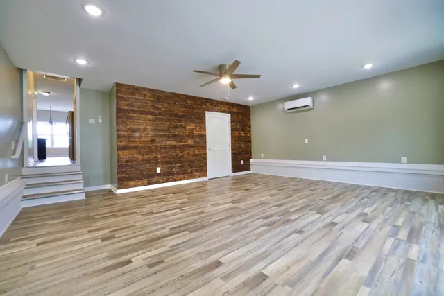 an empty room with wooden floor and a ceiling fan