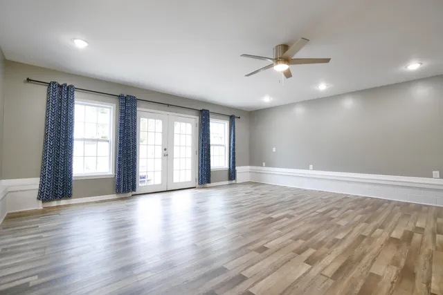 a view of an empty room with wooden floor and a window