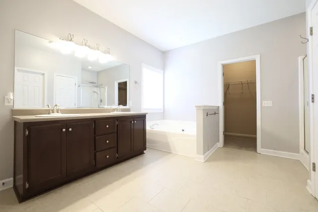 a spacious bathroom with a double vanity sink a large mirror and a bathtub