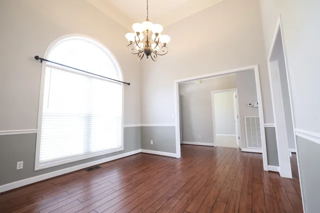 a view of a room with wooden floor chandelier and a window