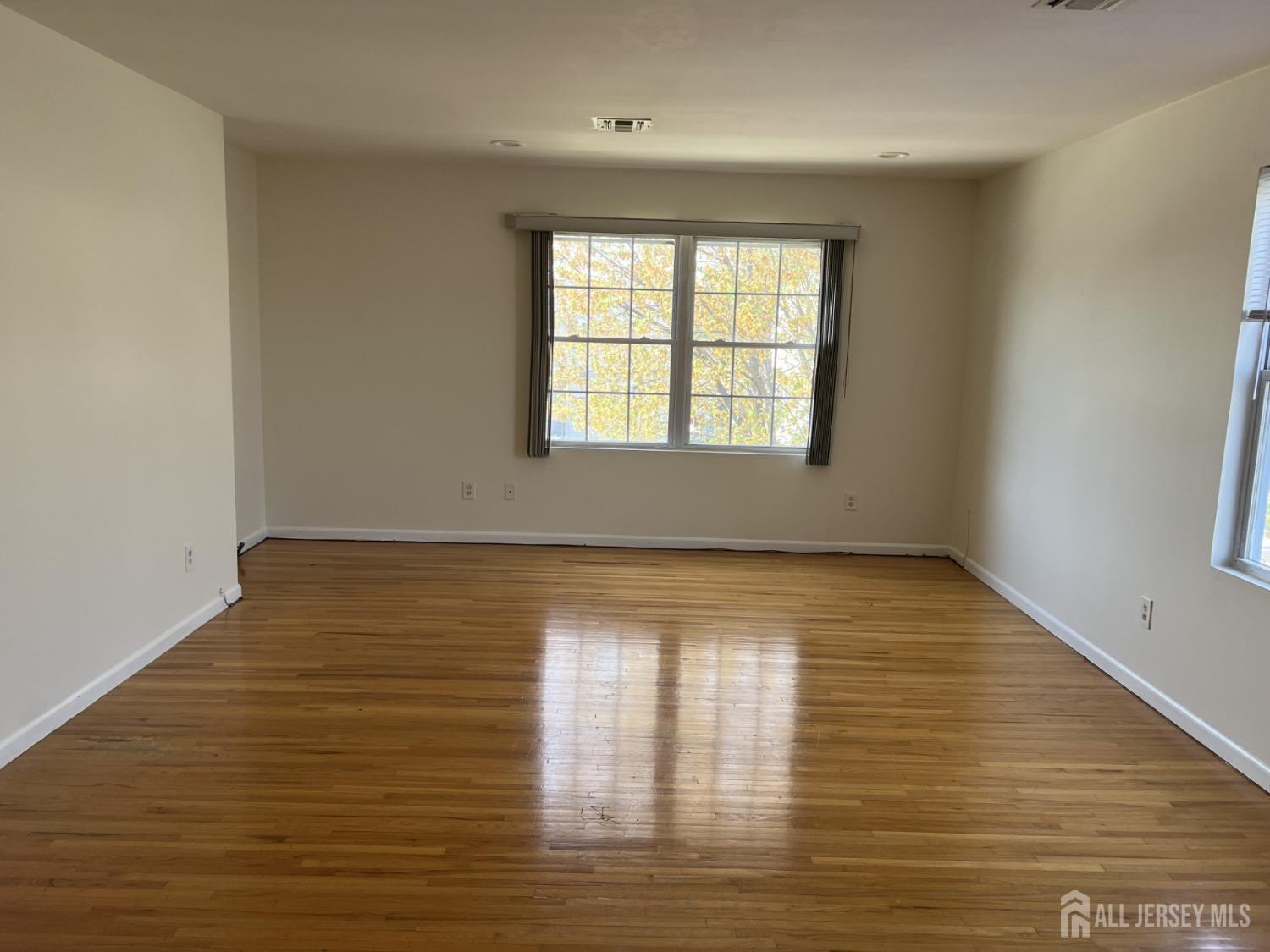 22 North Whittier Street, Unit B Carteret, NJ 07008 - Photo 23 of 27 a view of an empty room with wooden floor and a window