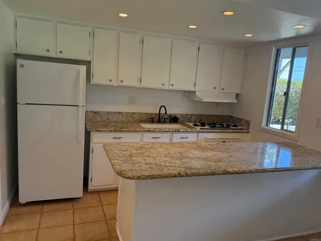 a kitchen with granite countertop a refrigerator a stove a sink a counter space and cabinets