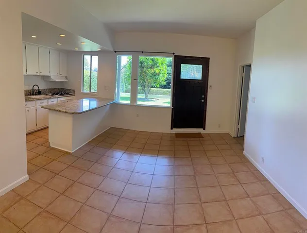 a kitchen with granite countertop a rug a stove a microwave and white cabinets