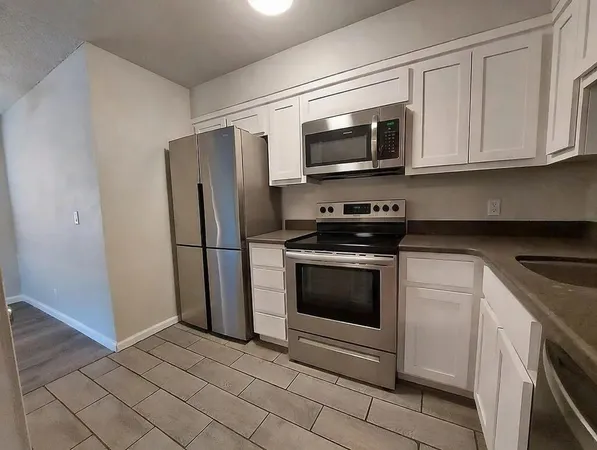 a kitchen with stainless steel appliances granite countertop white cabinets a microwave a sink and a refrigerator