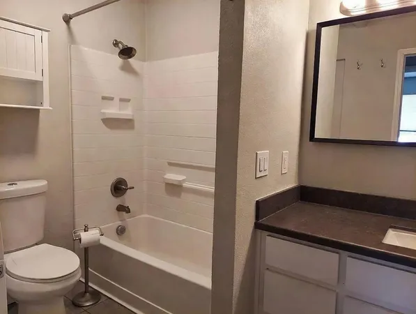 a bathroom with a granite countertop sink a toilet and shower