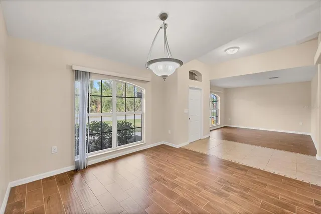 an empty room with wooden floor fan and windows