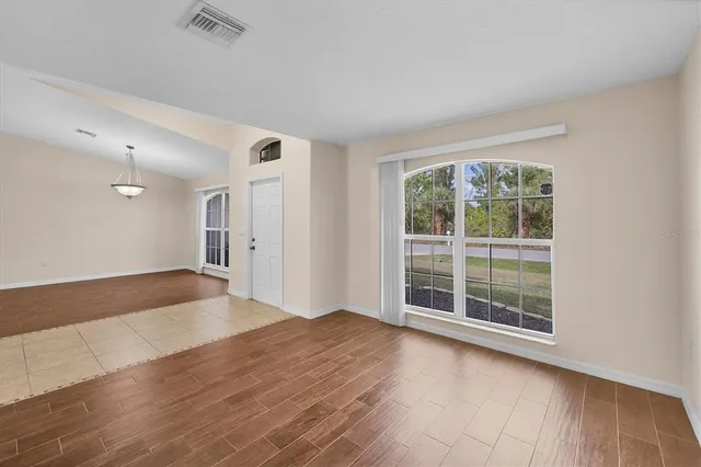 an empty room with wooden floor fan and windows