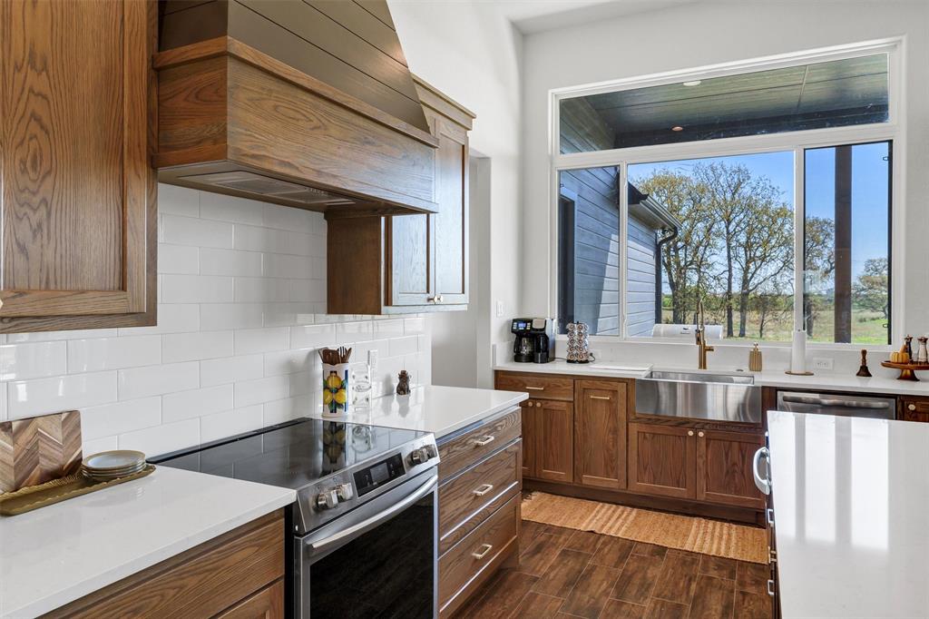 2105 Rattler Way Tolar, TX 76476 - Photo 12 of 30 a kitchen with stainless steel appliances sink stove and wooden cabinets