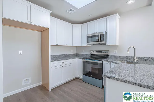 a kitchen with granite countertop white cabinets and stainless steel appliances