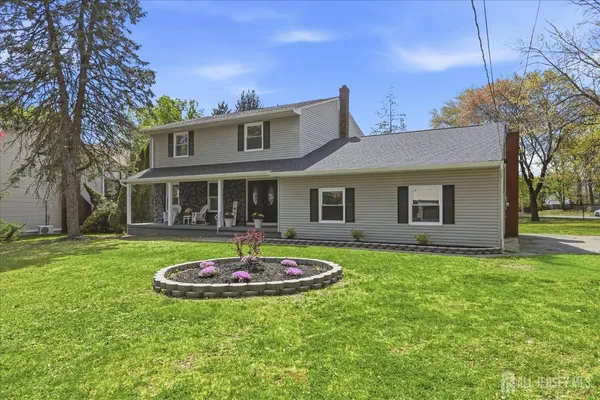 a front view of a house with a garden and trees