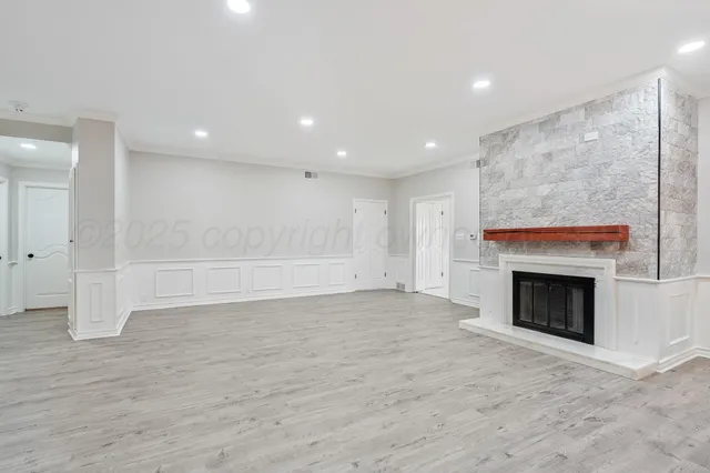 an empty room with wooden floor fireplace and windows