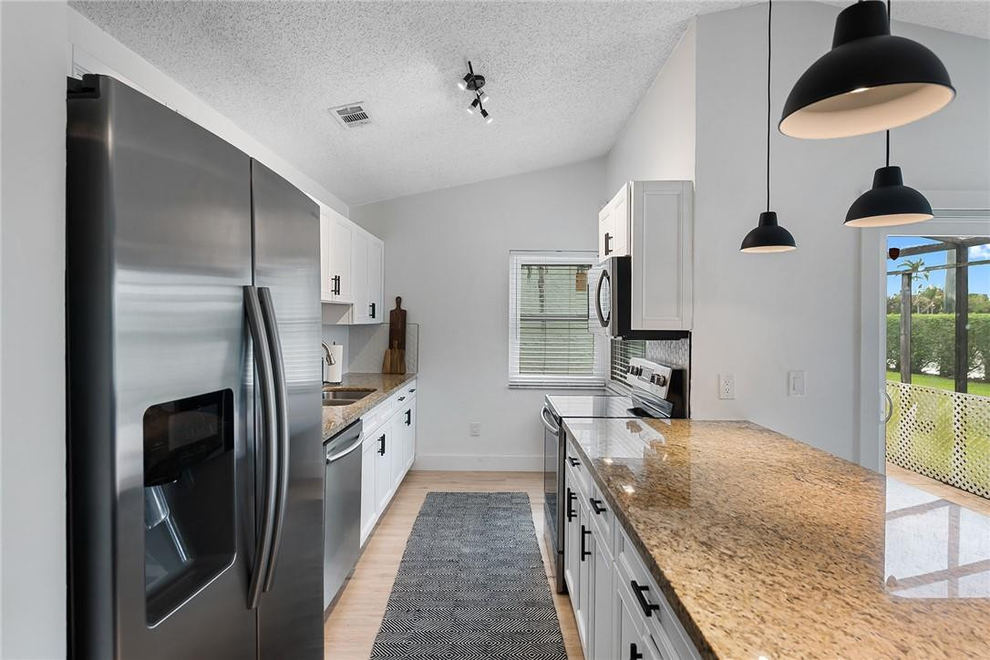 9085 Southwest 20th Street, Unit D Boca Raton, FL 33428 - Photo 8 of 25 a kitchen with granite countertop a sink stainless steel appliances and cabinets