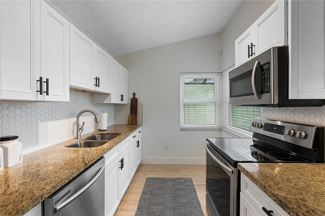 9085 Southwest 20th Street, Unit D Boca Raton, FL 33428 - Photo 9 of 25 a kitchen with stainless steel appliances granite countertop a sink stove and microwave